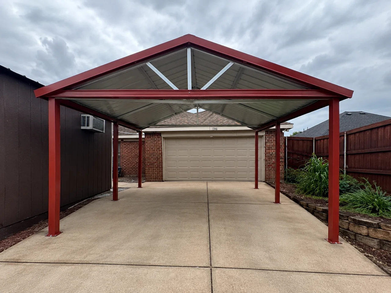 Red gable roof red iron carport installed over a residential driveway in Fort Worth, Texas